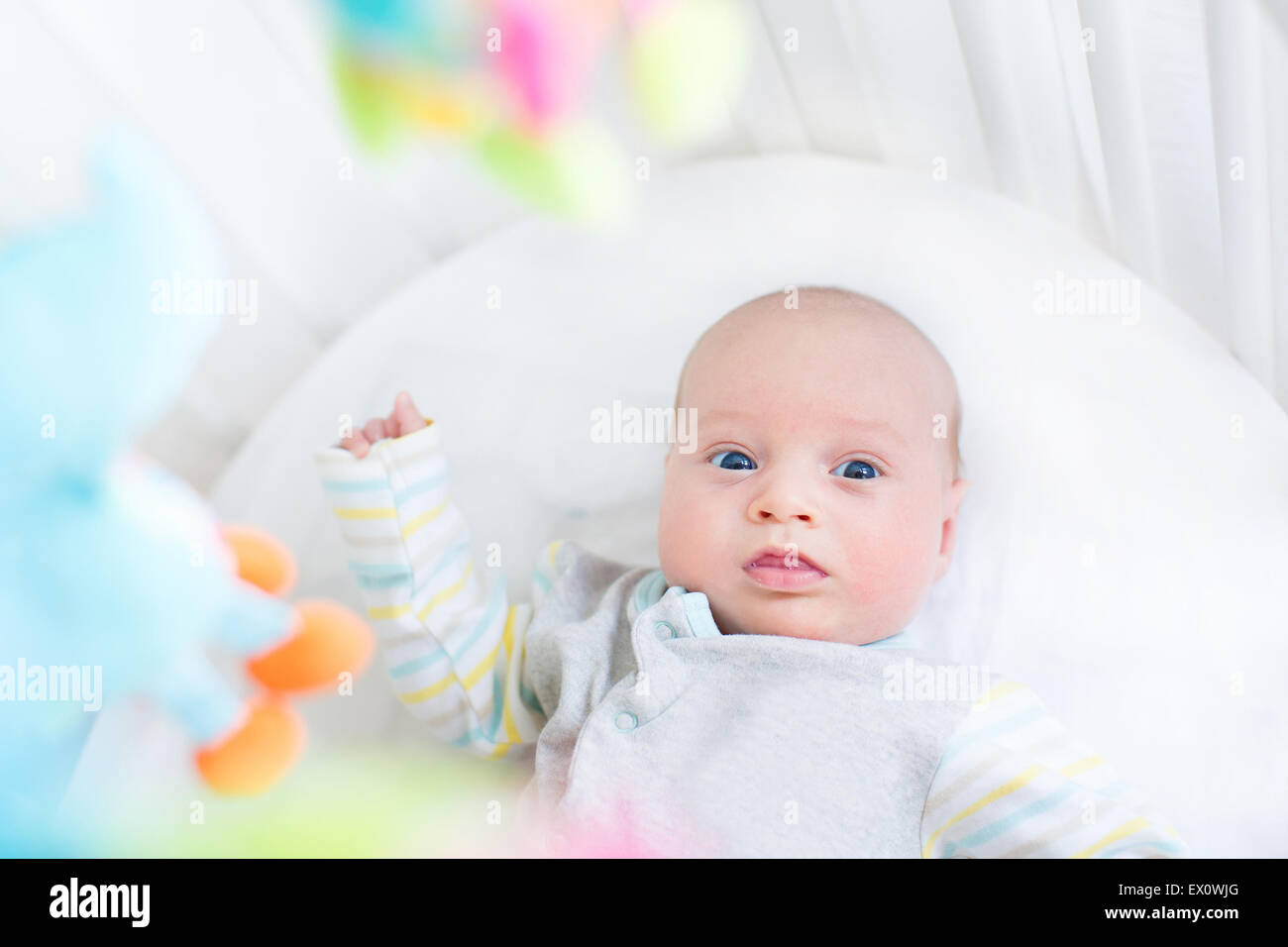 Cute little newborn baby in a white crib with colorful toys Stock Photo Alamy