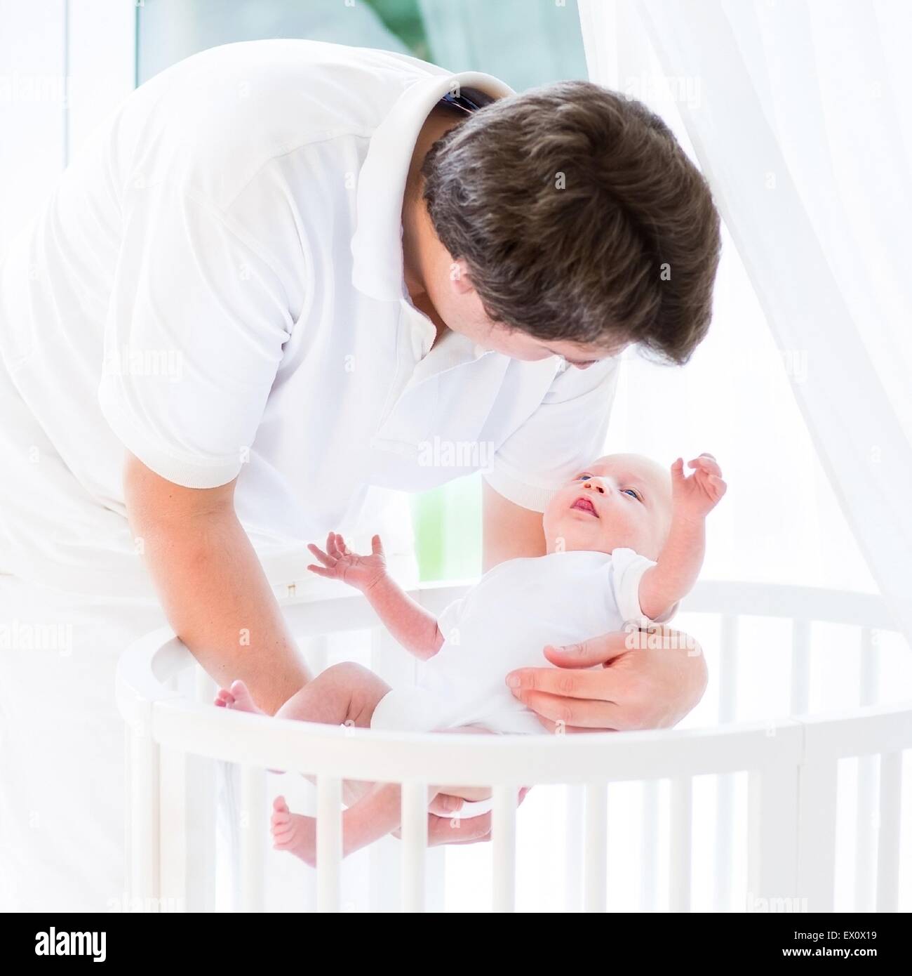 Young Happy Father Holding His Newborn Baby Next To A White Round