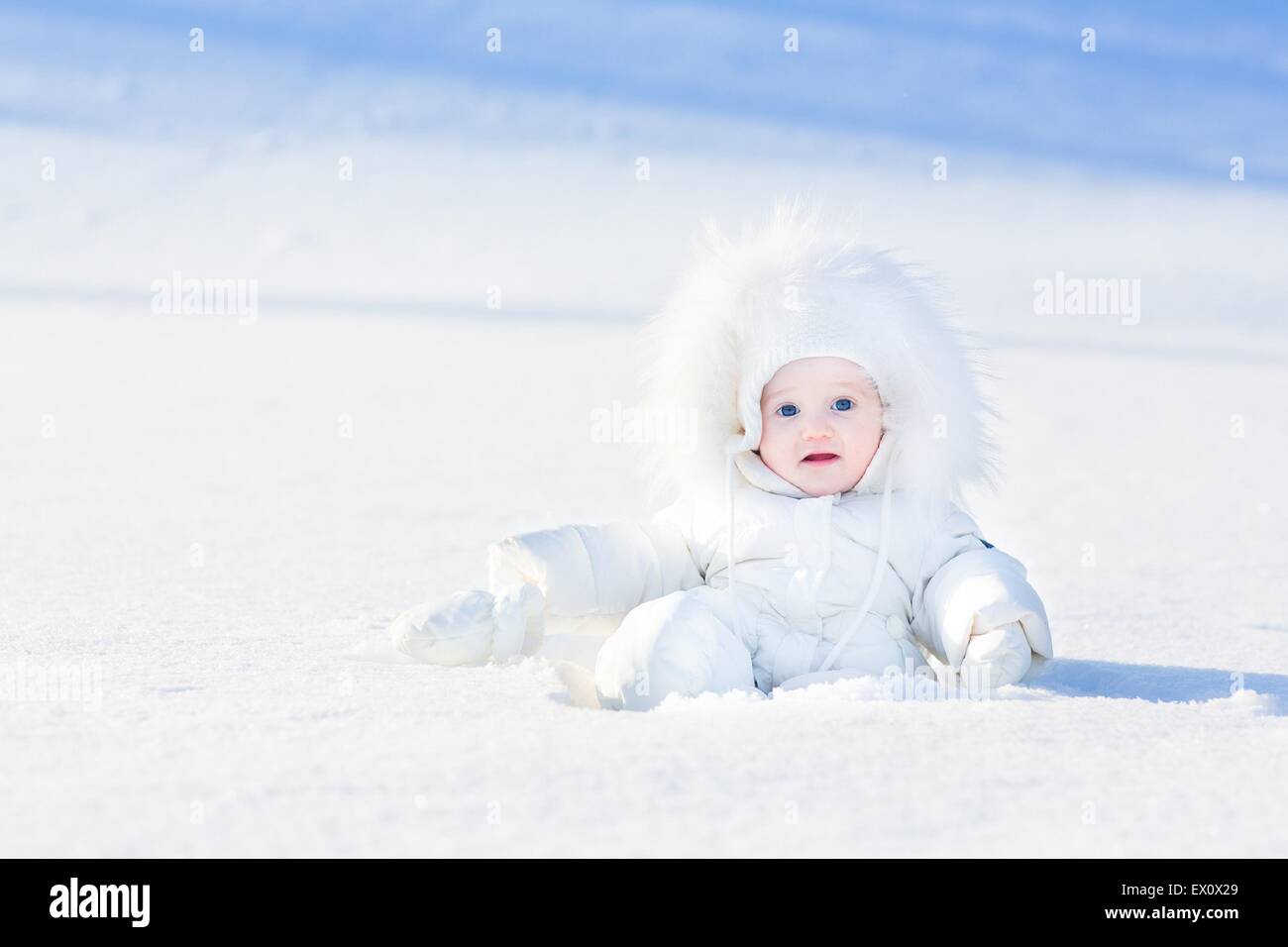 Cute little baby in a white jacket playing in snow Stock Photo