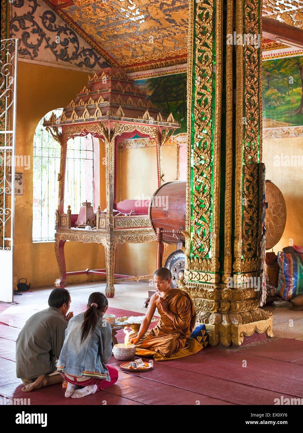 Young Buddhist couple pray with a monk inside Wat Si Muang, Vientiane, Laos, P.D.R. Stock Photo