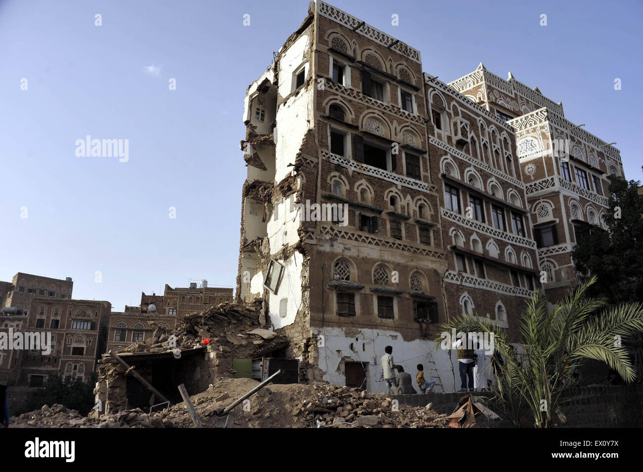 Sanaa, Yemen. 3rd July, 2015. Yemenis stand near a historical building destroyed by the airstrike of Saudi-led coaltion forces in the Old City of Sanaa in Sanaa, Yemen, on July 3, 2015. The United Nations Educational, Scientific and Cultural Organization (UNESCO) World Heritage Committee on July 2 added two sites in Yemen on the List of World Heritage in Danger: the Old City of Sanaa and the Old Walled City of Shibam. Credit:  Hani Ali/Xinhua/Alamy Live News Stock Photo