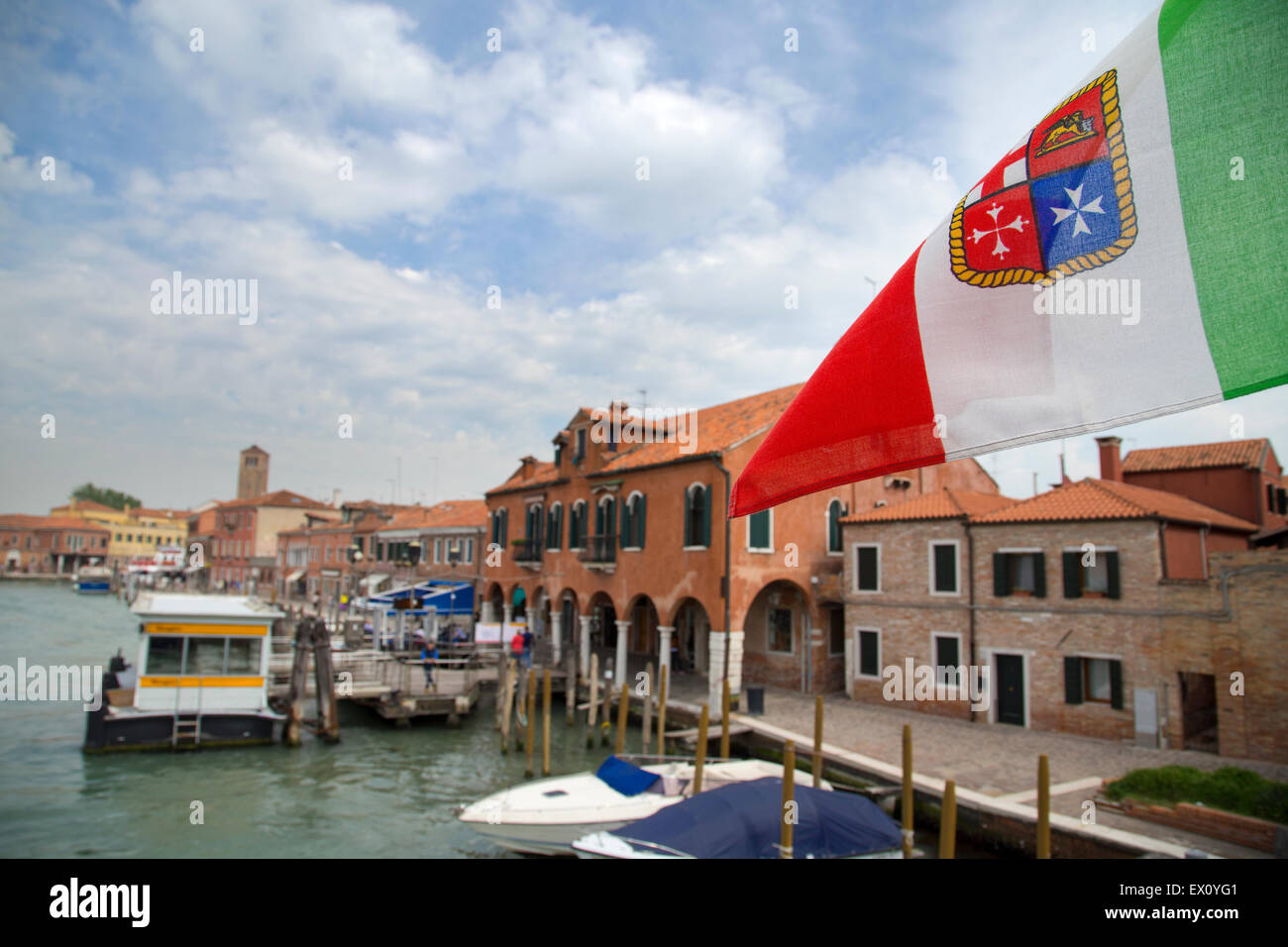 Italian flag closeup view with island of Murano shore on the background, Italy Stock Photo