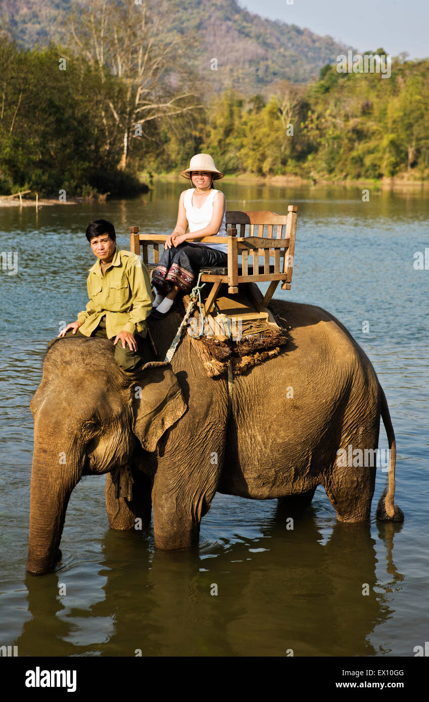 A Lao woman and mahout ride an elephant on the Khan River Stock Photo ...