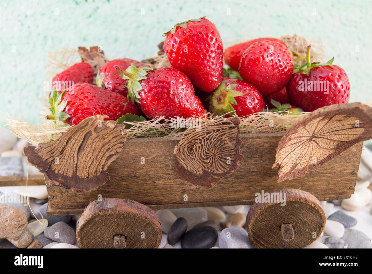 Bunch of fresh strawberries stacked on miniature old carts Stock Photo
