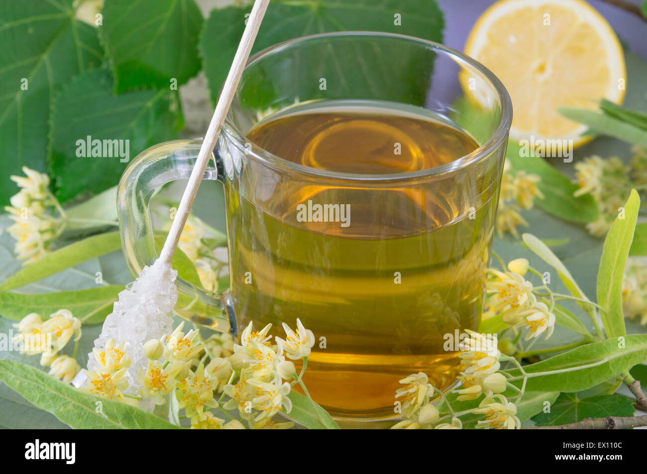 Cup of natural lime tea with sugar stick, lemon and lime flowers Stock Photo
