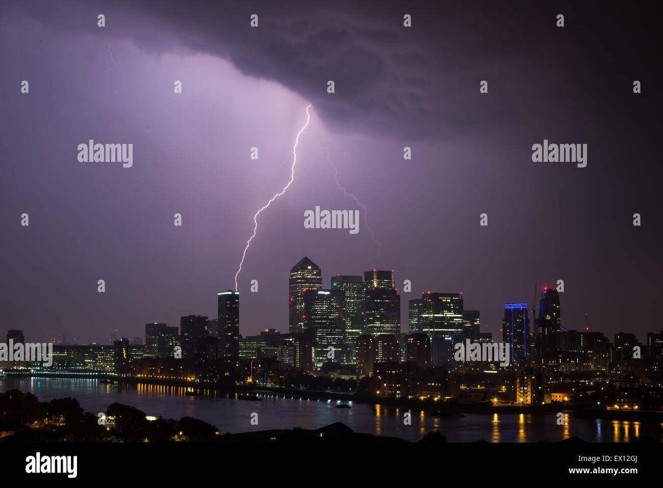 A lightning bolt strikes Landmark East Tower flat complex during a brief but dramatic electrical storm over Canary Wharf business park buildings Stock Photo