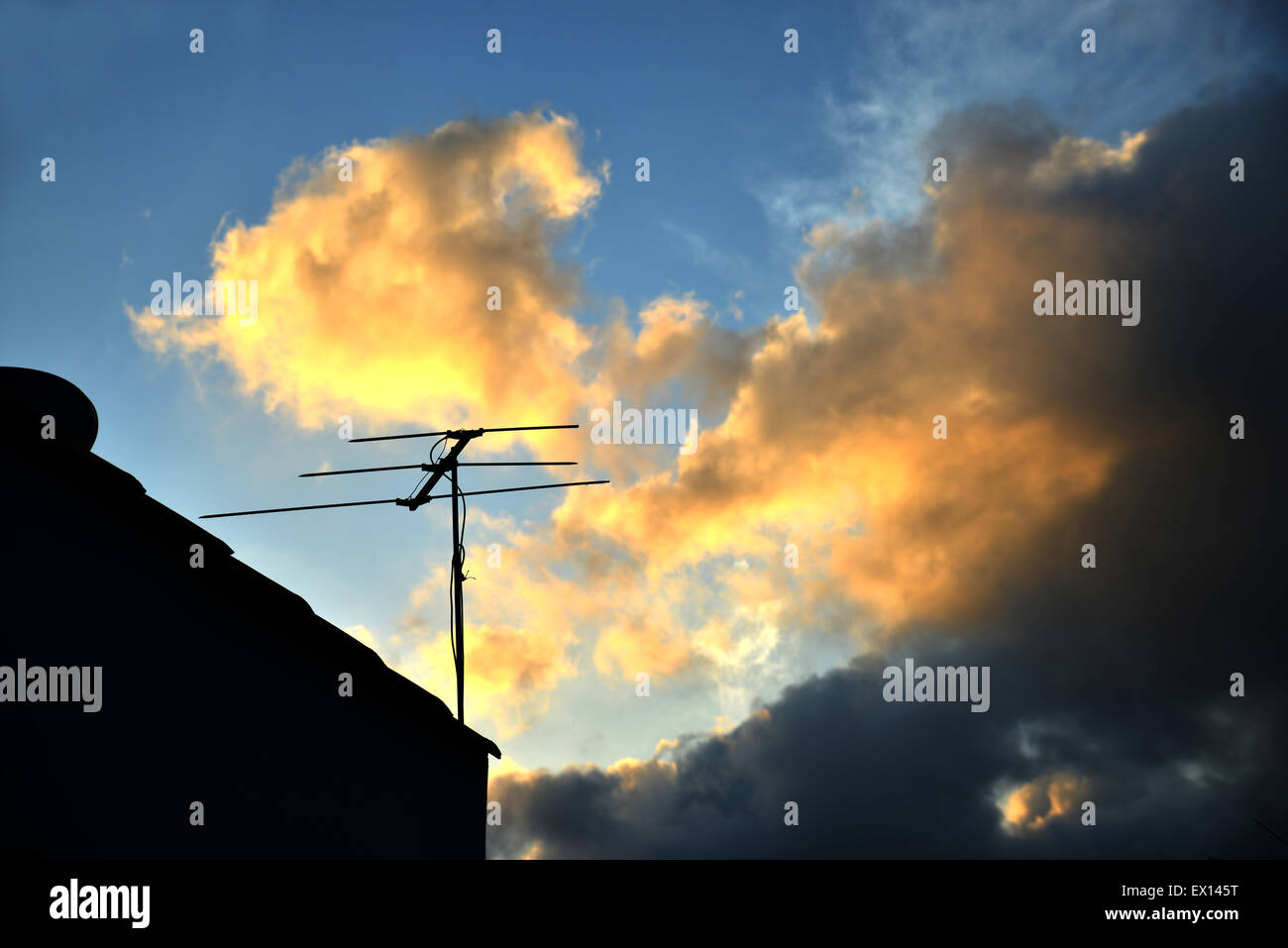 Silhouette image of an old analog roof tv antenna with a sunset background Stock Photo