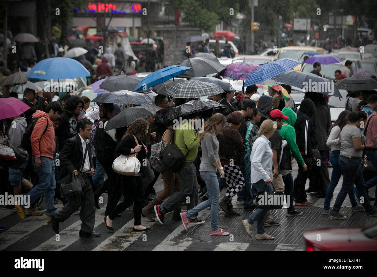Mexico City, Mexico. 3rd July, 2015. People walk in the rain in Mexico City, capital of Mexico, on July 3, 2015. According to local press, a low air pressure from the northwest, west and center of Mexico, combined with the entrance of humidity from the Pacific ocean and the Gulf of Mexico, will favor the potential of rains. Credit:  Alejandro Ayala/Xinhua/Alamy Live News Stock Photo