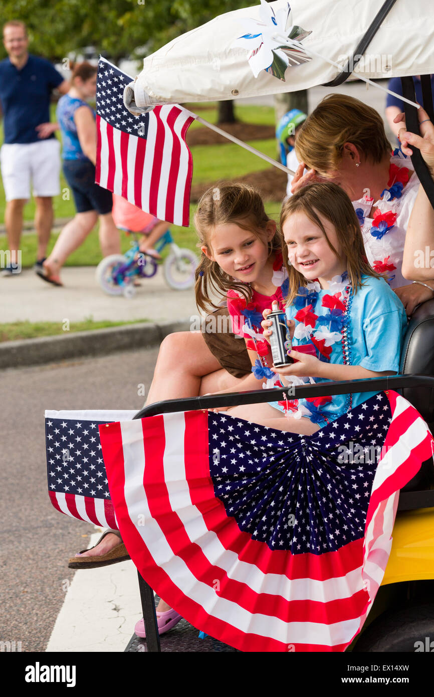 A family rides in their golf cart decorated with bunting and American flags during the Daniel Island Independence Day parade July 3, 2015 in Charleston, South Carolina. Stock Photo