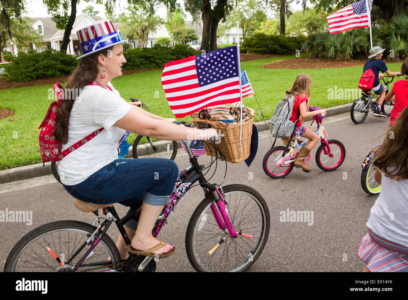A family rides bicycles decorated with bunting and American flags during the Daniel Island Independence Day parade July 3, 2015 in Charleston, South Carolina. Stock Photo