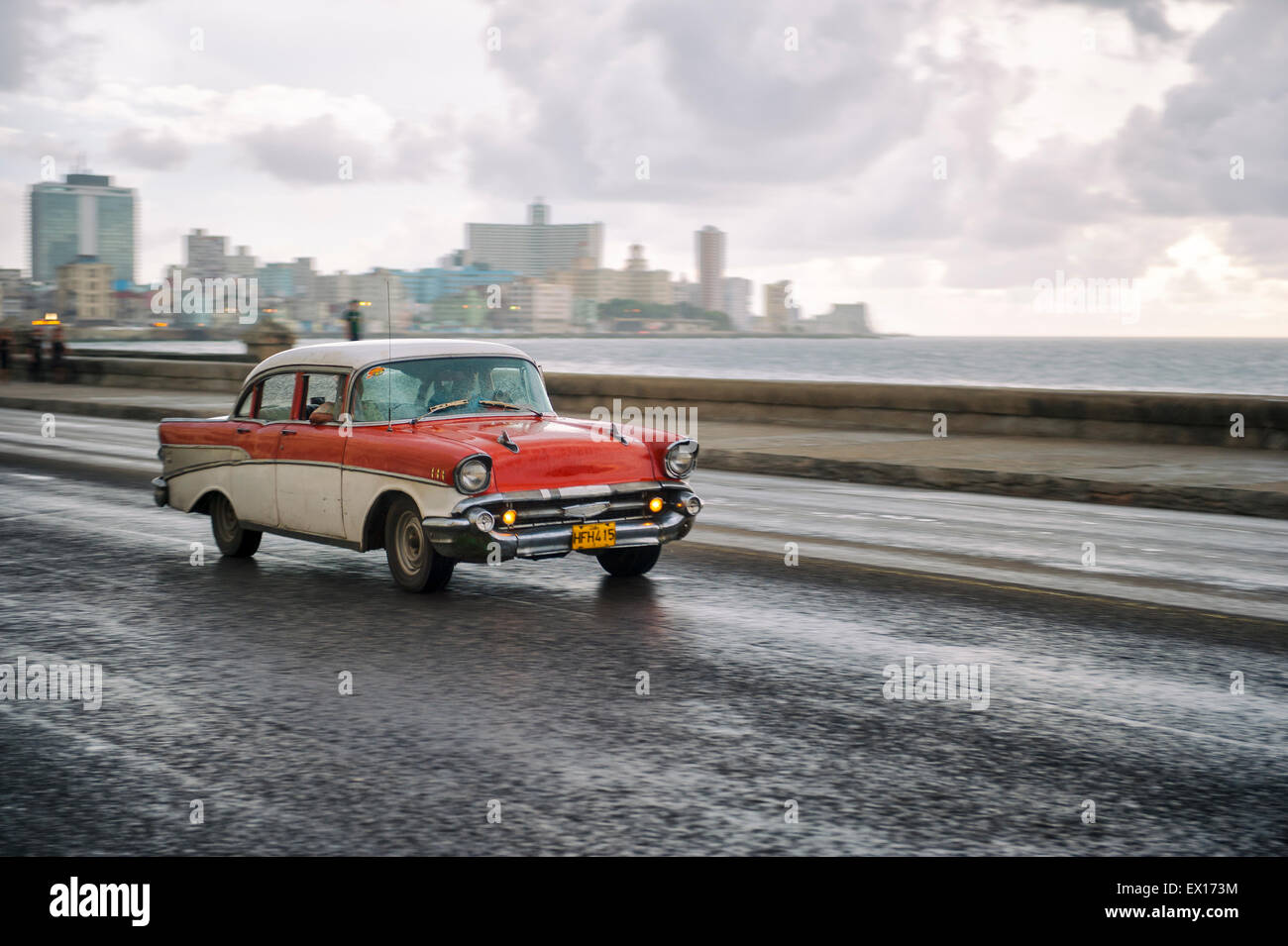HAVANA, CUBA - JUNE 13, 2011: Classic old fashioned 50s car passes in front of the city skyline along the seafront Malecon road. Stock Photo