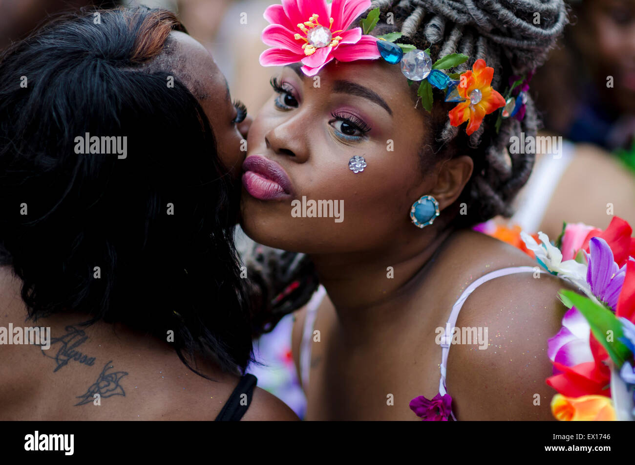 NEW YORK CITY, USA - JUNE 28, 2015: Young woman decorated with colorful flowers kisses a friend in greeting at the Pride Parade. Stock Photo