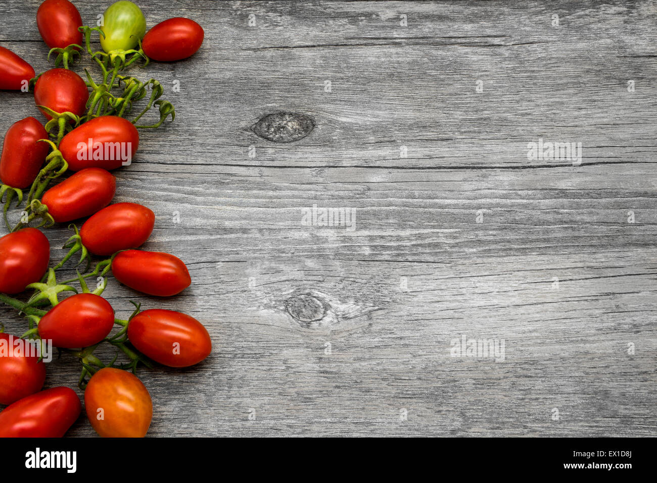 Cherry tomatoes on a gray wooden table. Vegetable border. Stock Photo