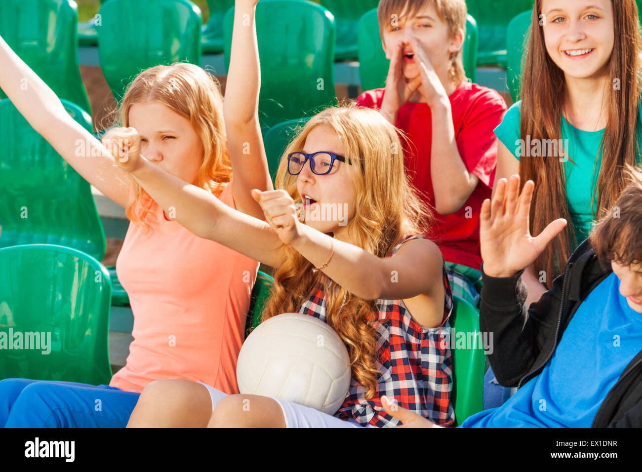 Teenagers cheer for team during game at stadium Stock Photo