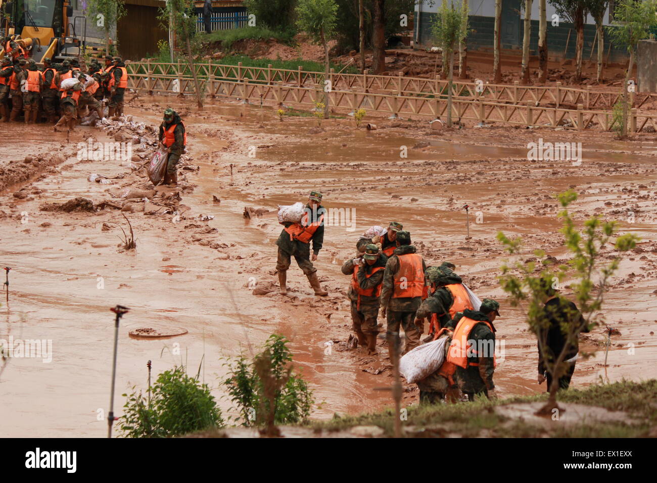 Zhangye, China's Gansu Province. 4th July, 2015. Armed policemen carry sandbags to block flood water in Sunan County, northwest China's Gansu Province, July 4, 2015. A heavy rainfall caused landslide in Sunan on Saturday, damaging 63 houses. Seventy residents have been evacuated. Credit:  Cheng Xuelei/Xinhua/Alamy Live News Stock Photo
