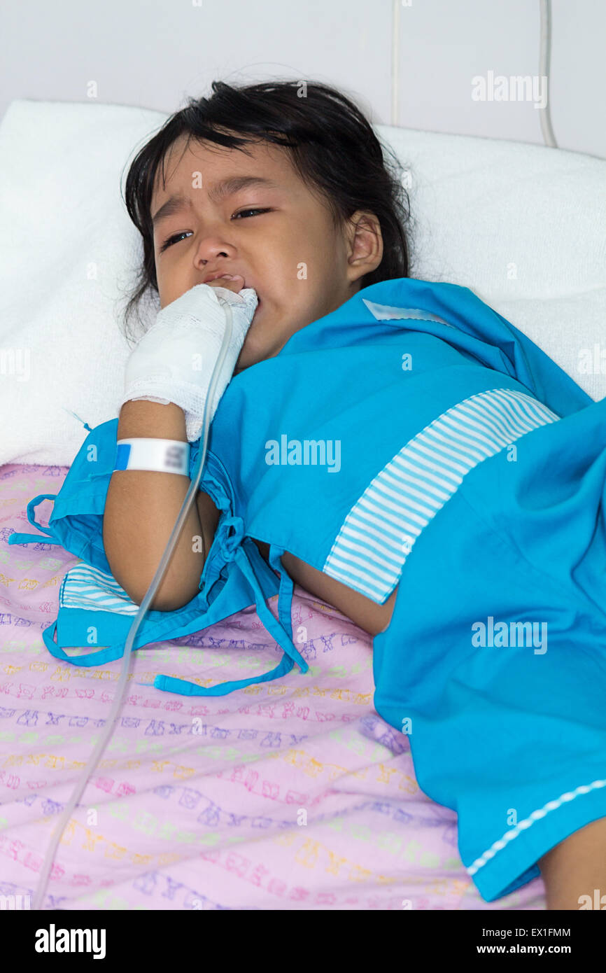 Illness little asian kids crying, asleep on a sickbed in hospital, saline intravenous (IV) on hand Stock Photo