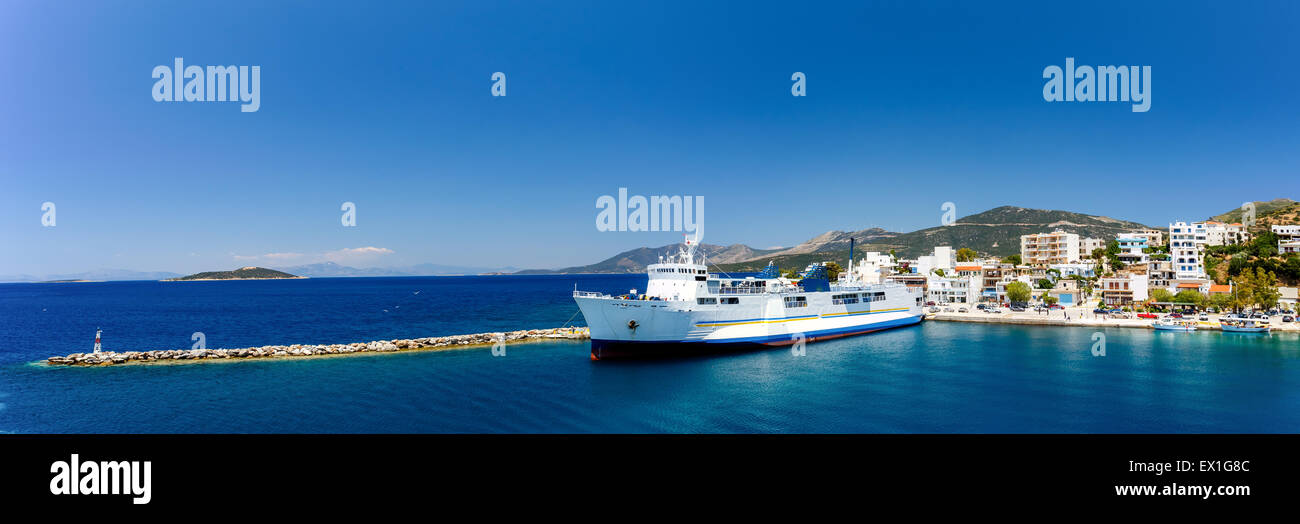 Marmari port with anchored ship and white houses against a blue sky and blue waters in Evia, Greece Stock Photo