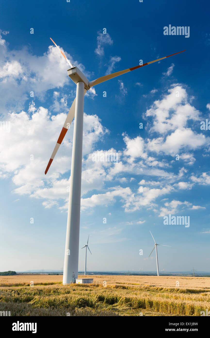 A close wind turbine in a wind park that seems to look down at smaller wind turbines in the background. Seen in the Eifel, Germa Stock Photo