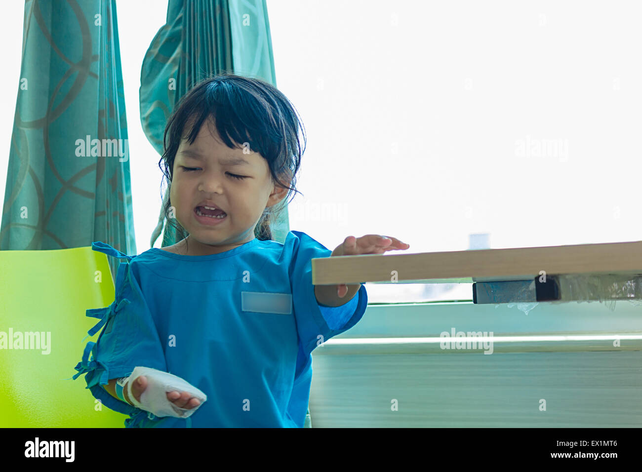 Illness asian kids sit on a chair in hospital, saline intravenous (IV) on hand Stock Photo