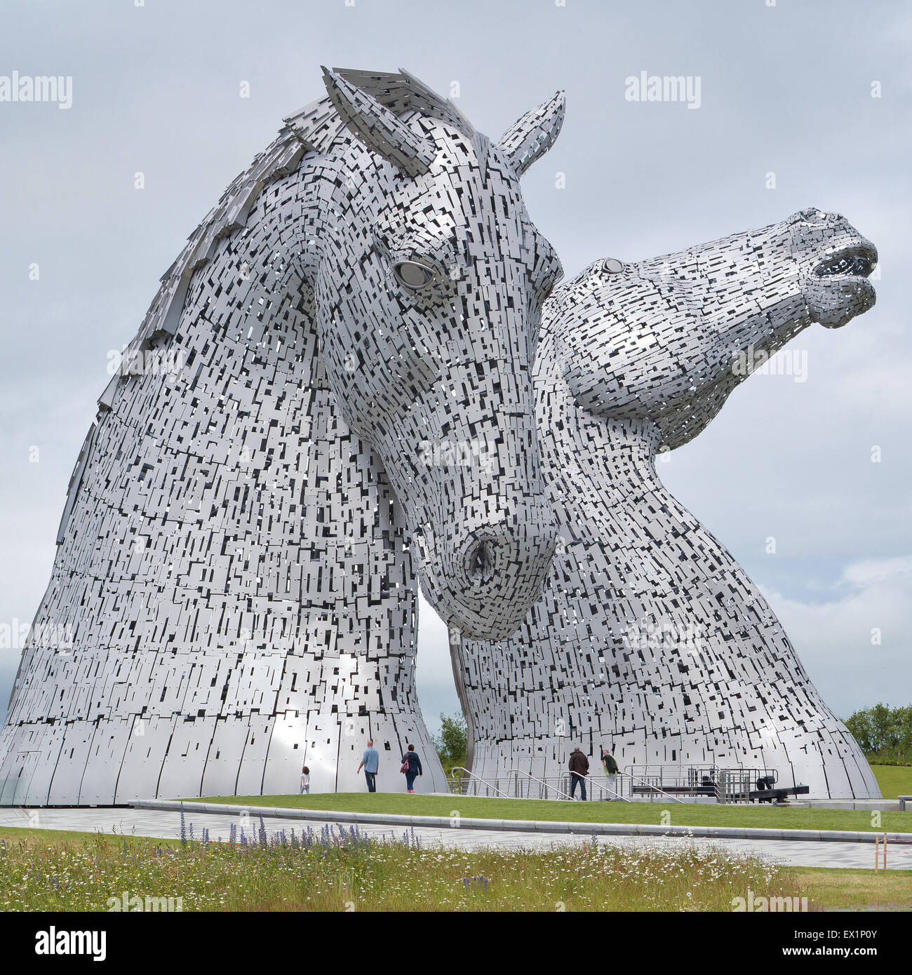 Visitors dwarfed by The Kelpies - giant equine sculptures in Falkirk, Scotland by artist Andy Scott Stock Photo