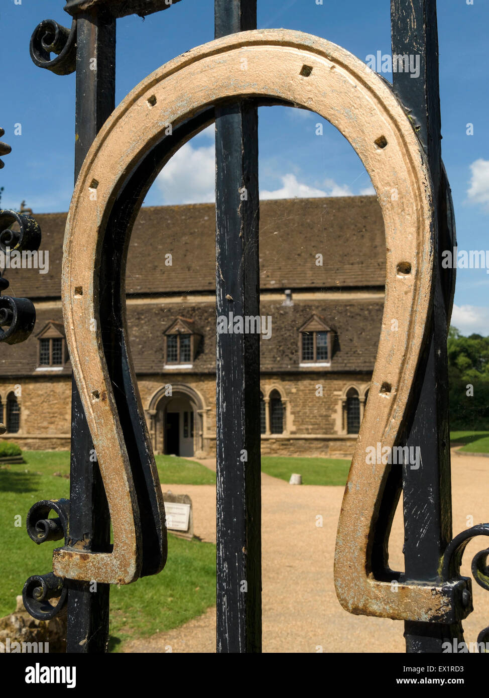 Golden horseshoe on the black wrought iron gates of Oakham Castle, with Great Hall beyond, Oakham, Rutland, England, UK. Stock Photo