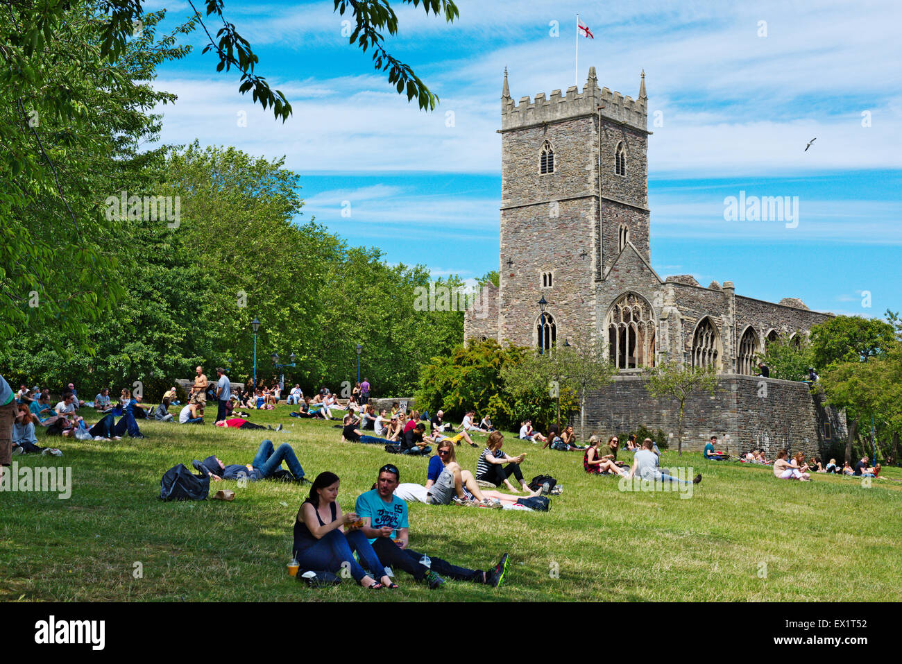 Summer sun people sitting on grass of Castle Park with derelict St Peter's Church Stock Photo