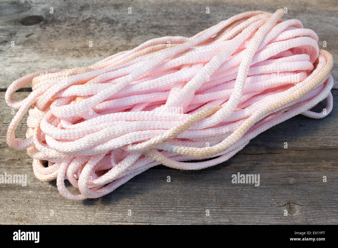 White Rope and Textured Wood, Coil of white rope set against highly textured wood. Stock Photo