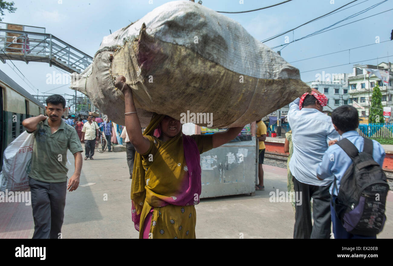 Kolkata, Indian state West Bengal. 4th July, 2015. An Indian woman carries heavy loads in Kolkata, capital of eastern Indian state West Bengal, July 4, 2015. India has released new socio-economic and caste census data which covers the period between 2011 and 2013 to show the wealth, living conditions and other details of the country's 1.2 billion people. Nearly one third are landless, and half derive their income mainly from manual labor. © Tumpa Mondal/Xinhua/Alamy Live News Stock Photo