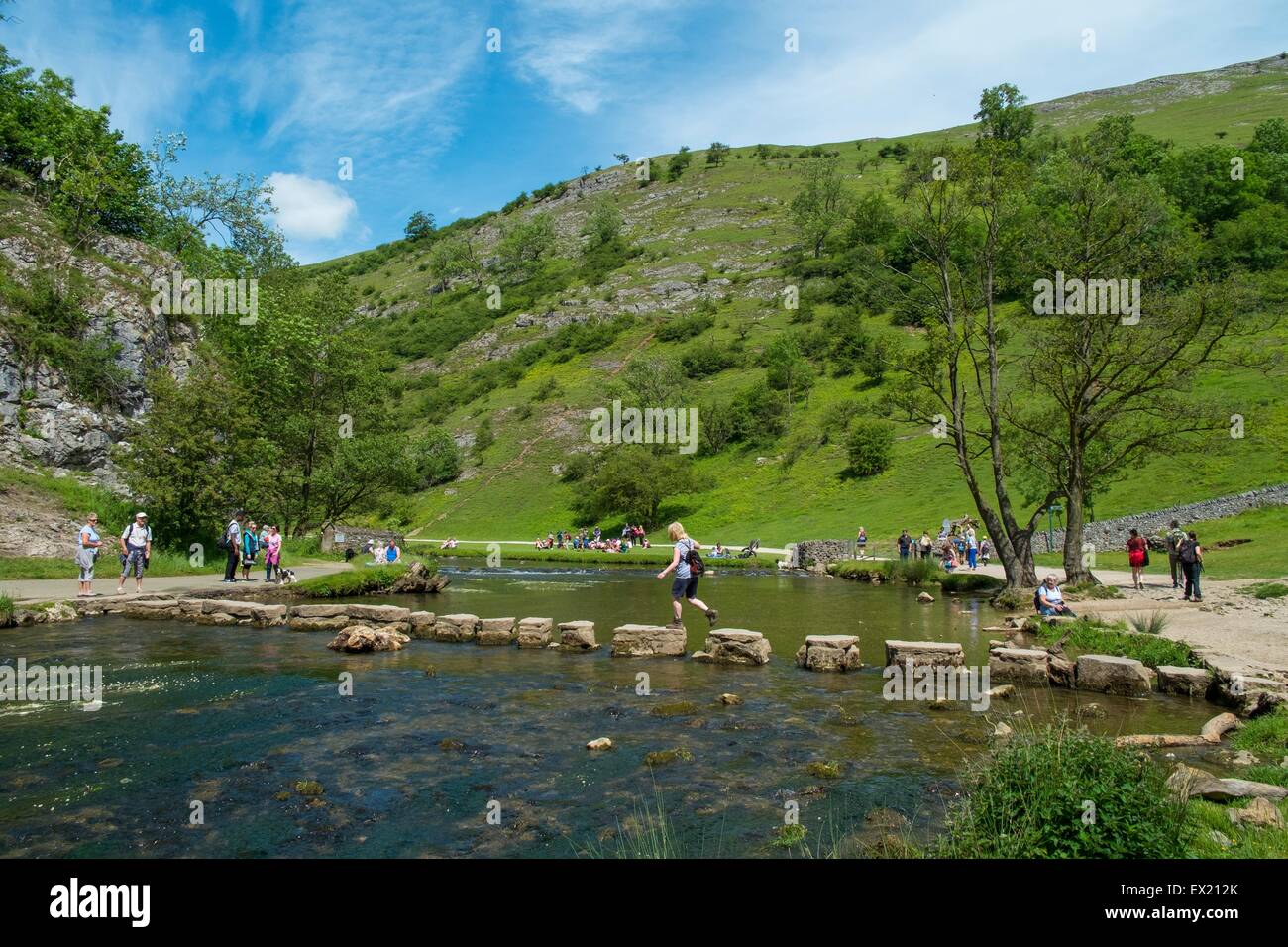 Tourists walking across the stepping stones in Dovedale. Stock Photo