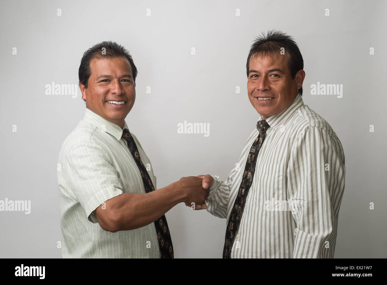 Hispanic businessmen shaking hands, negotiating and smiling. Stock Photo