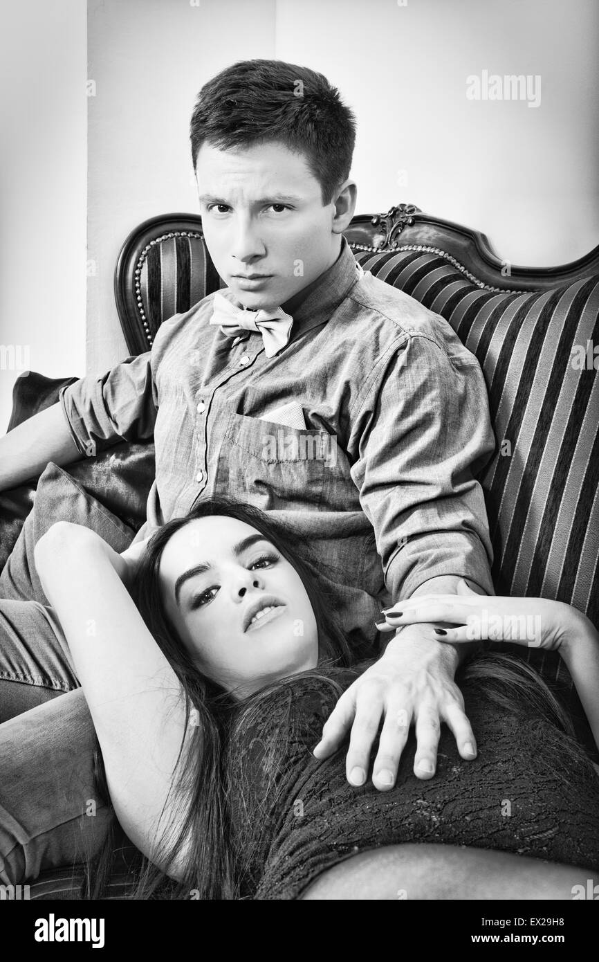 Young couple sitting on the couch, black  and white photography. Fashion photo of attractive young couple. Male and female model Stock Photo