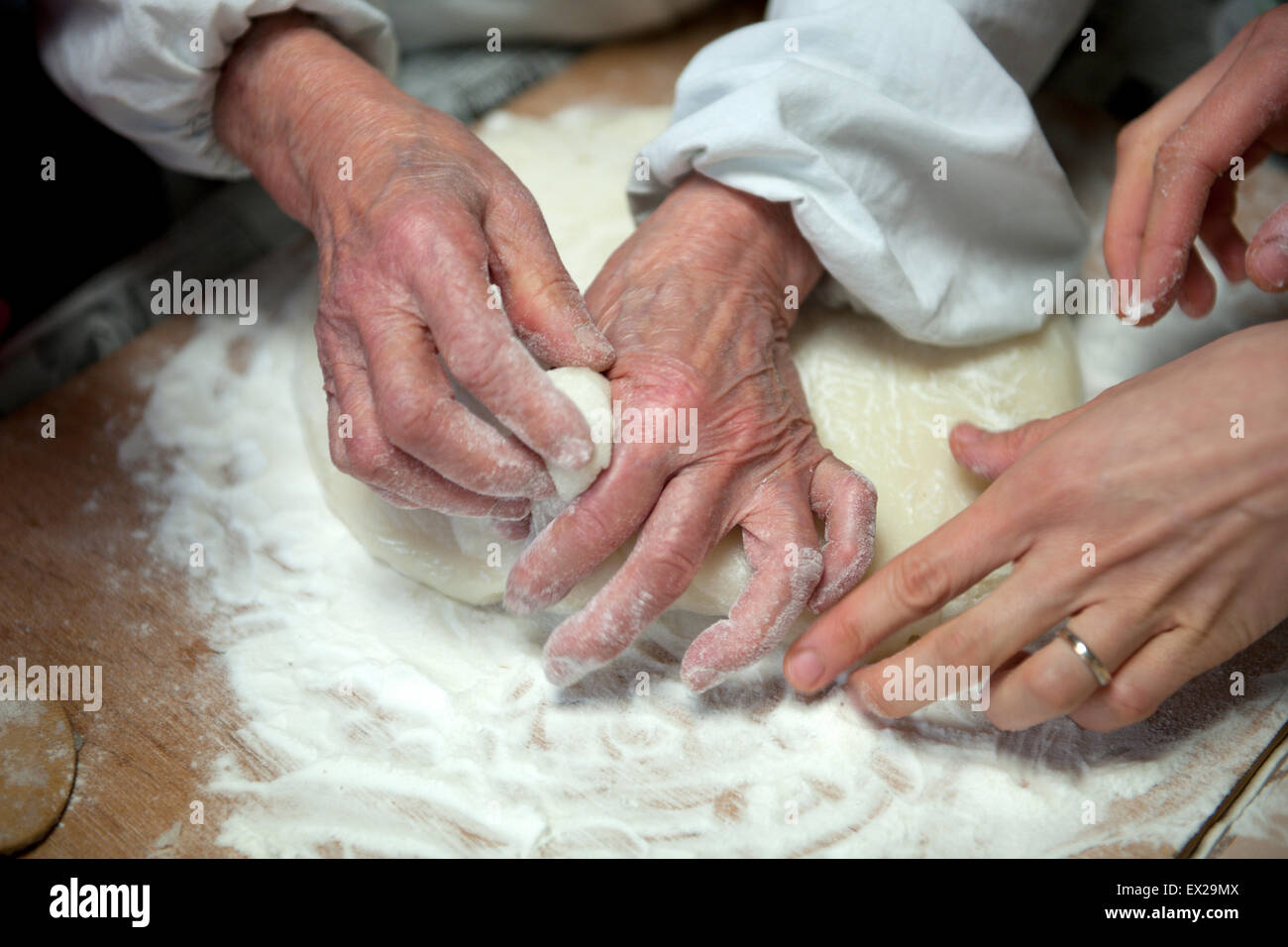 Senior lady making traditional Japanese rice cake - mochi. Close up of aged and younger hands. Stock Photo