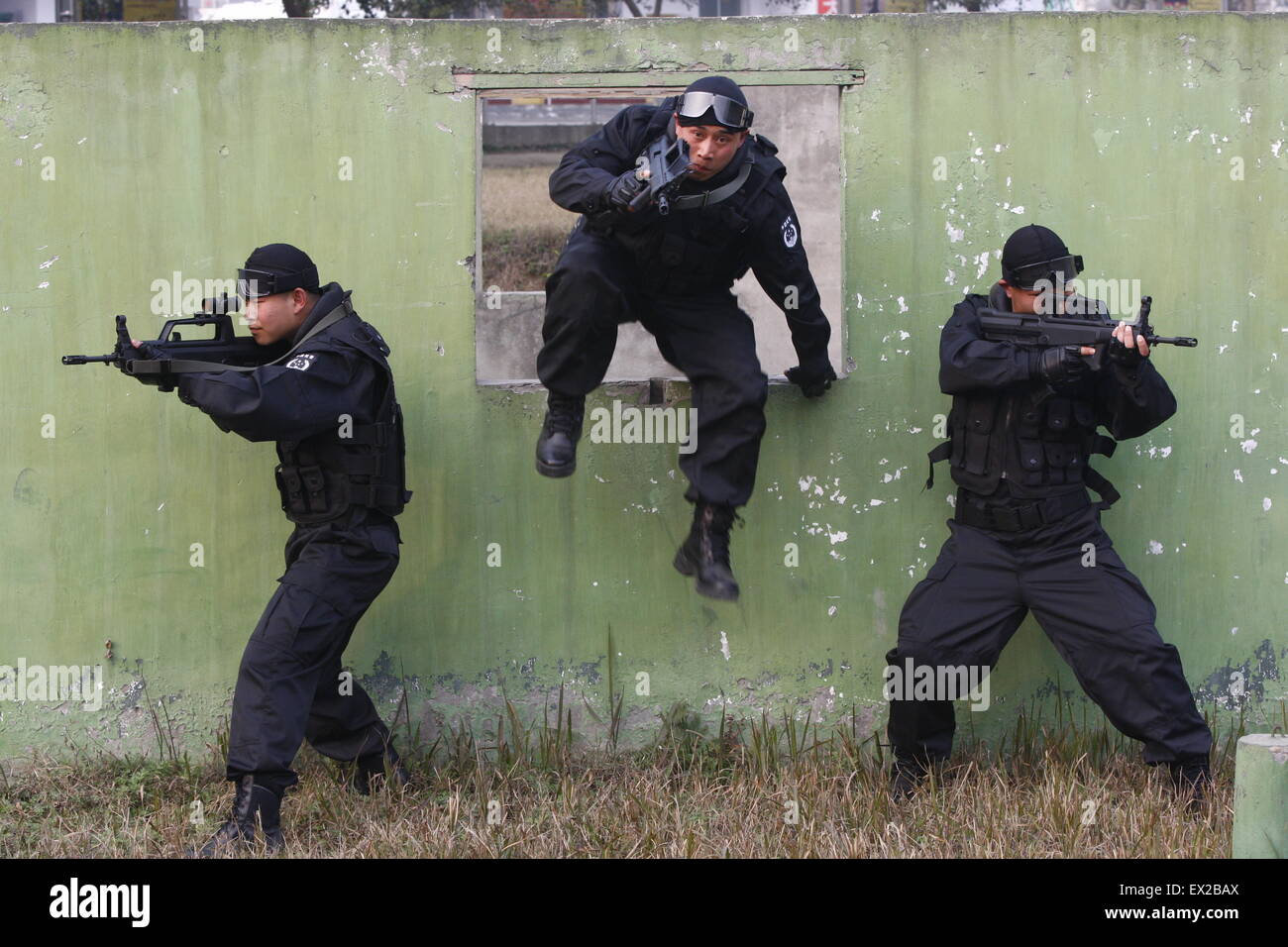 A paramilitary policeman demonstrates shooting while stepping over barriers to recruits during a training session at a military Stock Photo