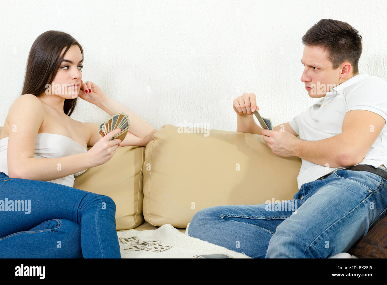 Sceptic young couple cheating each other in card game. Girl is bluffing and boyfriend is suspicious. Game is heating up. Suspici Stock Photo