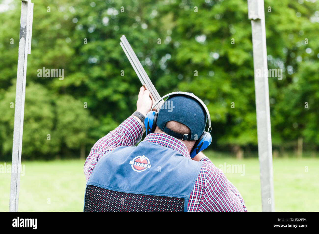 A man wearing safety ear defenders prepares to shoot a shotgun Stock Photo