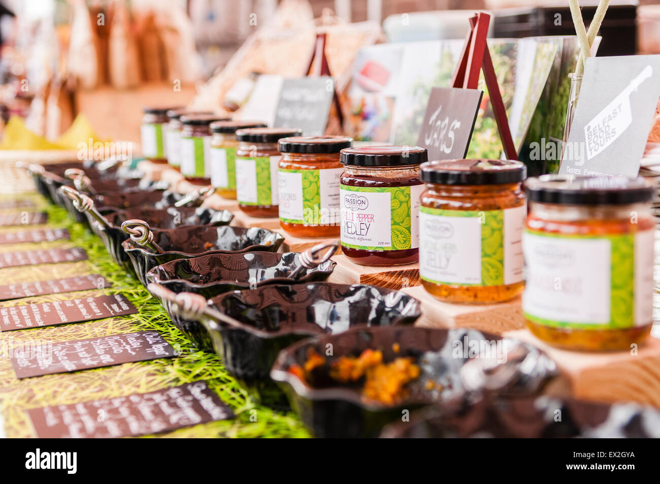 A row of jams, chutneys and pastes on sale at a market stall, with bowls for samples. Stock Photo