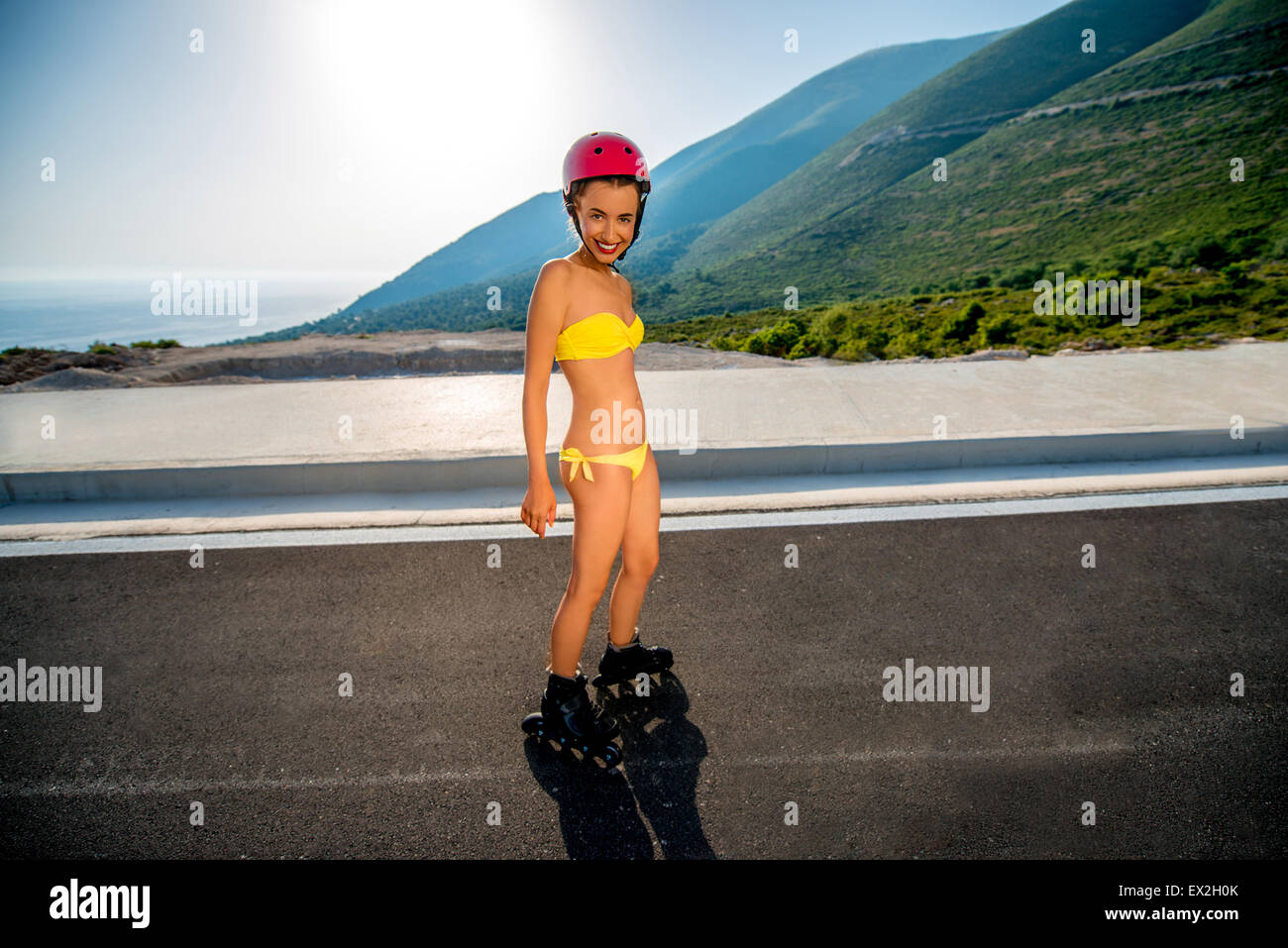 Woman in swimsuit with rollers on the highway Stock Photo