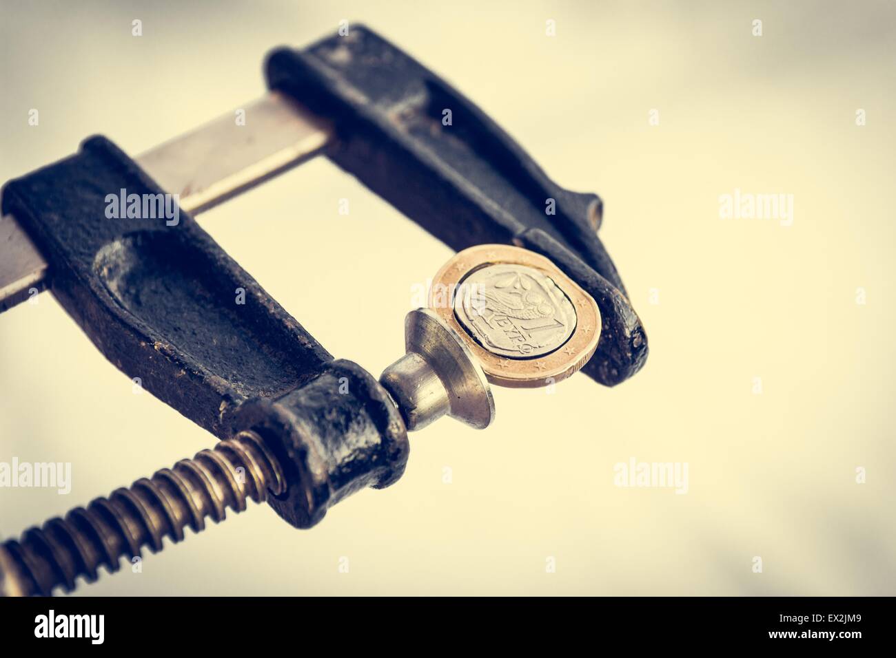 Greek Euro coin squezzed in clamp. Stock Photo