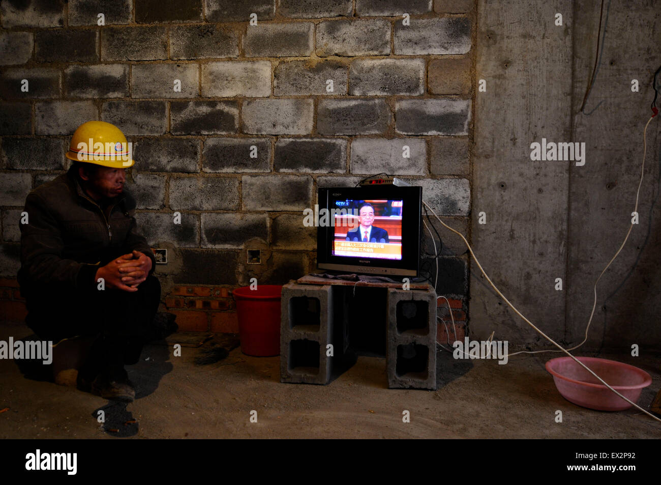 A labourer uses his mobile phone while watching a broadcast of China's Premier Wen Jiabao delivering his government work report Stock Photo