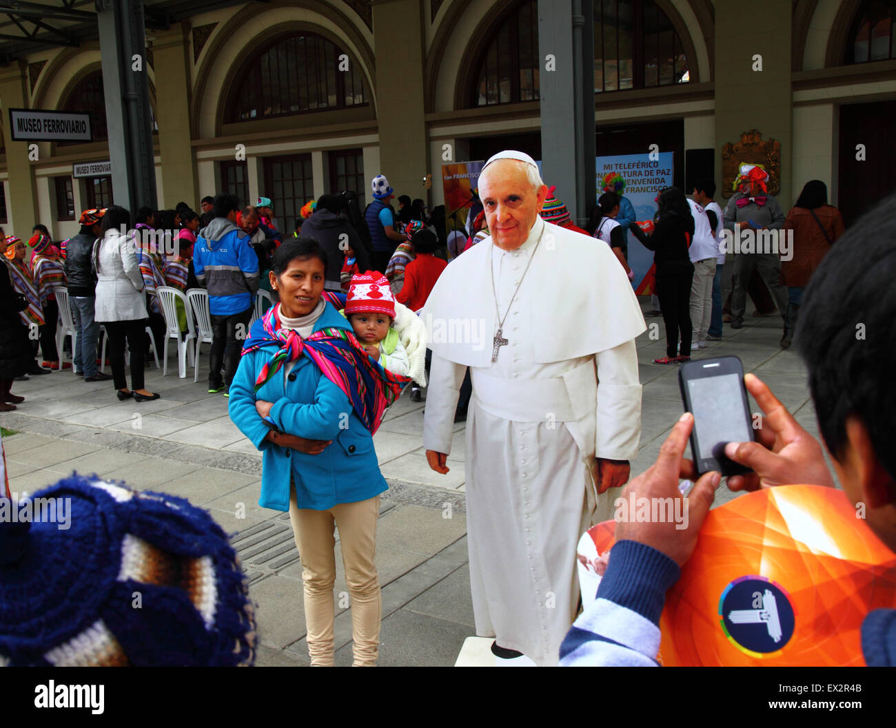 La Paz, Bolivia, 5th July 2015. A local lady and her baby pose for a photo with a life size cardboard cutout of Pope Francis at an event to celebrate his forthcoming visit to Bolivia. Pope Francis will visit La Paz on 8th July during his 3 day trip to Bolivia. Stock Photo