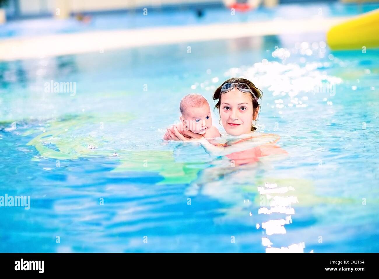 Young beautiful mother and her newborn baby enjoying swimming in a pool