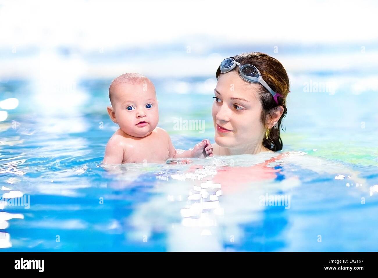 Adorable two months old baby boy enjoying swimming in a pool with his