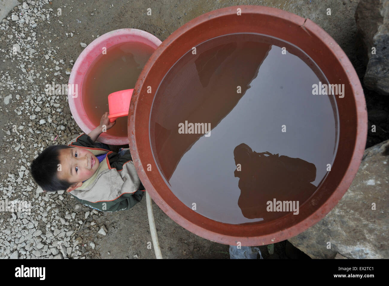 A boy carries a container as he stands on a partially dried-up reservoir in Kaiyang county, Guizhou province, March 16, 2010. A Stock Photo