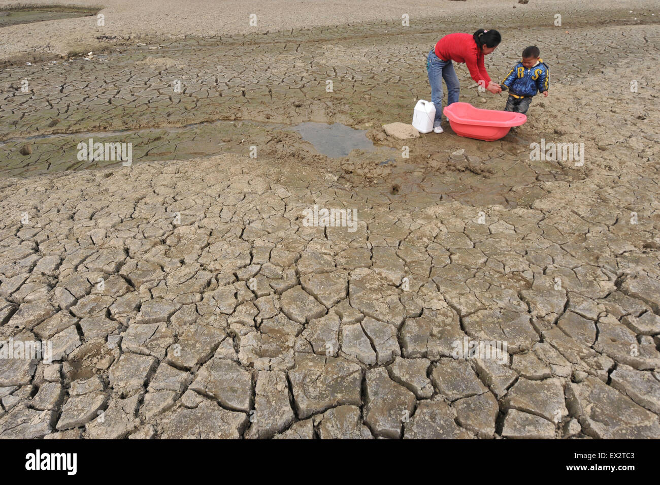 A boy carries a container as he stands on a partially dried-up reservoir in Kaiyang county, Guizhou province, March 16, 2010. A Stock Photo