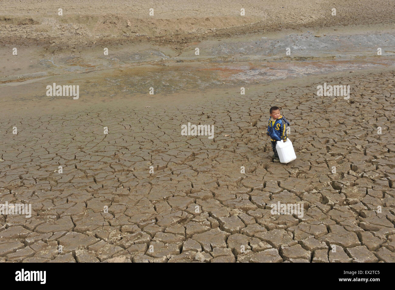 A boy carries a container as he stands on a partially dried-up reservoir in Kaiyang county, Guizhou province, March 16, 2010. A Stock Photo
