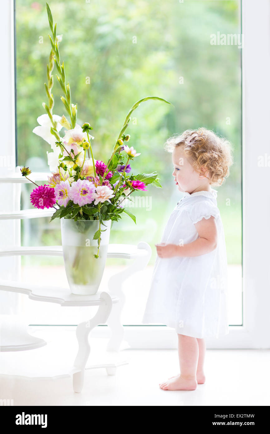 Beautiful Toddler Girl Watching Flowers In A Big Vase Next To A