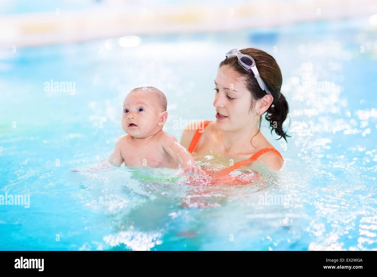 Young mother and her newborn baby having fun in a swimming pool Stock