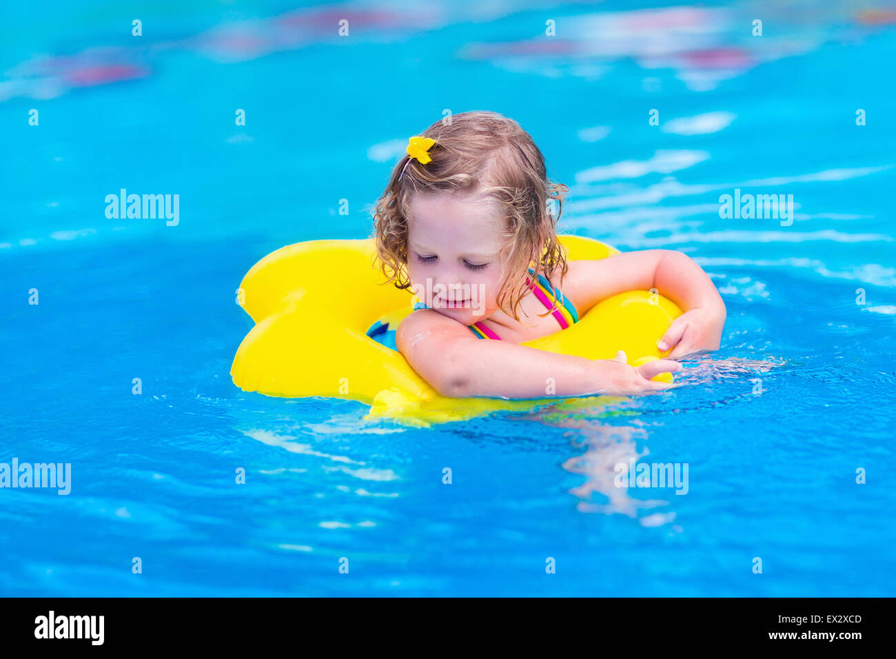 Kids in swimming pool. Children swim outdoors. Toddler child during vacation in a tropical resort with palm trees. Stock Photo