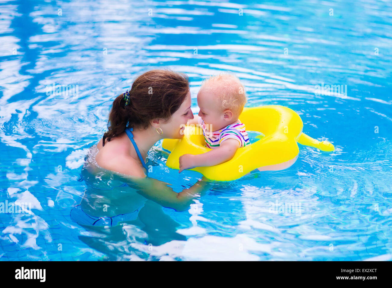 Mother and baby in swimming pool. Parent and child swim in a tropical