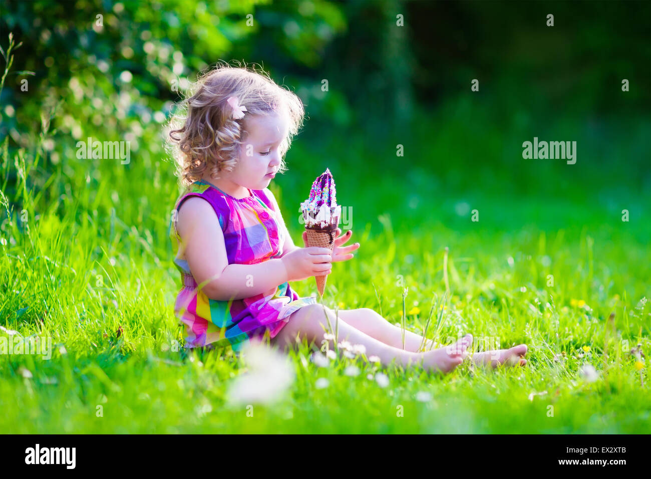 Child eating ice cream. Kids play outdoors enjoying sweet snack on a hot summer day. Children eat icecream. Stock Photo